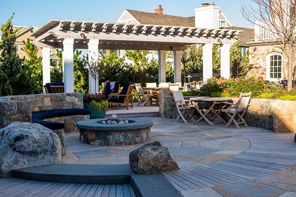 Circular bluestone patio with stone fire pit and pergola